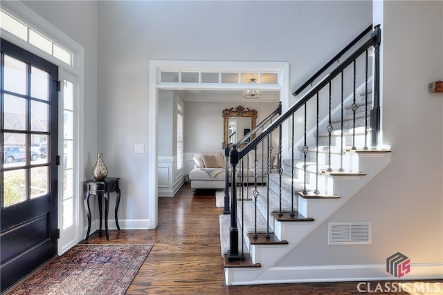 entrance foyer with stairs, wood finished floors, visible vents, and baseboards