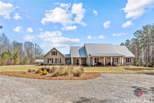 view of front of property with covered porch, metal roof, and a front lawn