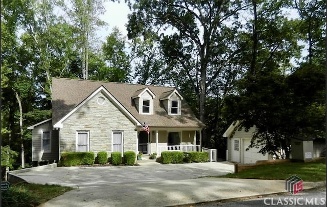 cape cod-style house with covered porch and an outbuilding