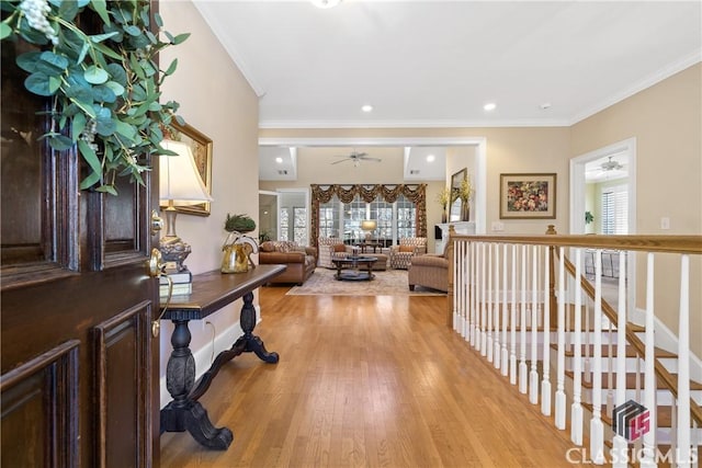 entrance foyer featuring light wood-style floors, ceiling fan, ornamental molding, and a healthy amount of sunlight
