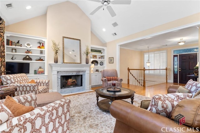 living room with wood finished floors, ceiling fan, built in shelves, and visible vents