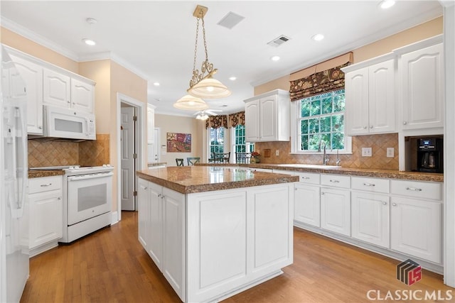 kitchen with a center island, white appliances, white cabinetry, and visible vents