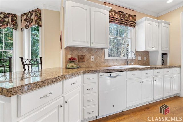kitchen featuring crown molding, white dishwasher, a wealth of natural light, and a sink