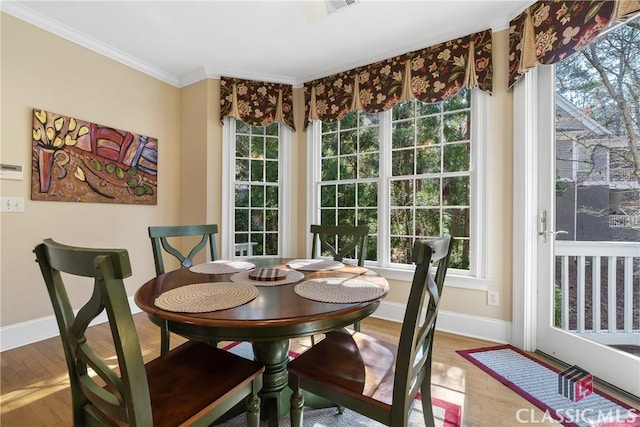 dining space featuring crown molding, baseboards, wood finished floors, and a wealth of natural light