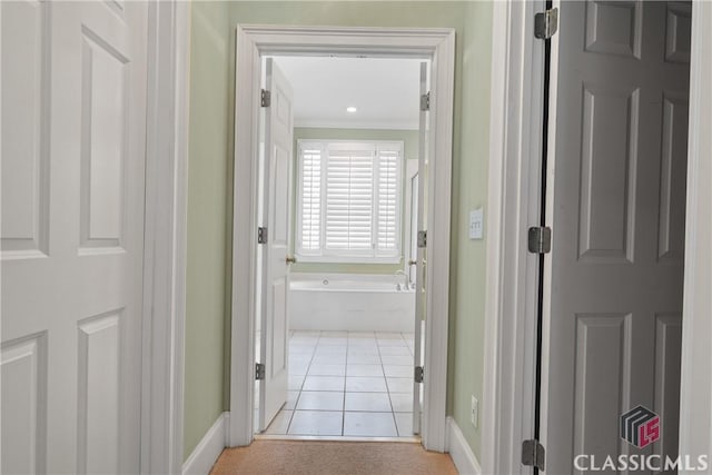 hallway with baseboards, crown molding, and light tile patterned floors