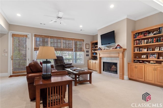 living area featuring ceiling fan, light colored carpet, ornamental molding, and a tile fireplace