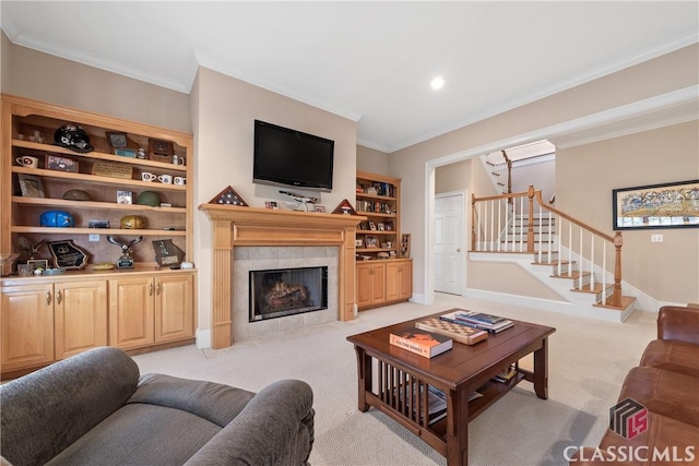 living area featuring light colored carpet, crown molding, built in features, a fireplace, and stairs