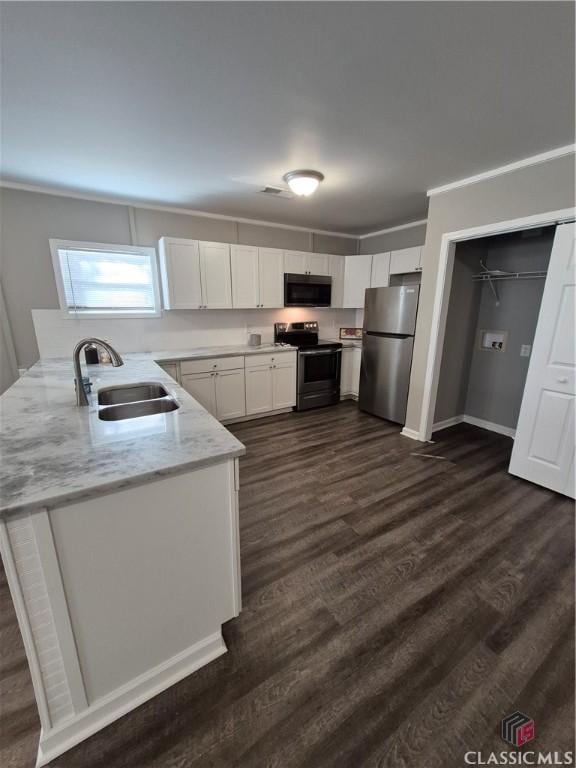 kitchen with stainless steel appliances, dark wood-style flooring, a sink, white cabinetry, and ornamental molding