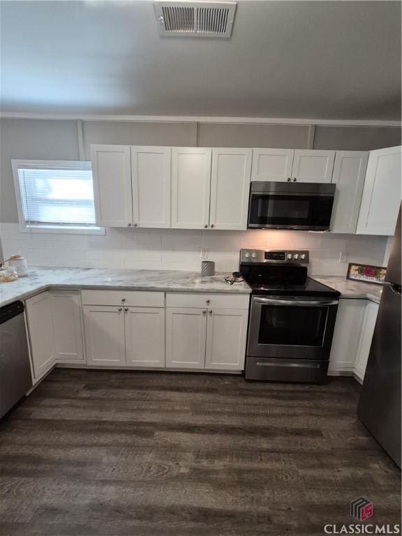 kitchen featuring visible vents, white cabinets, dark wood-style flooring, stainless steel appliances, and light countertops