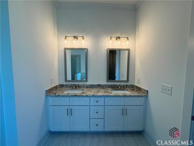 full bathroom with double vanity, a sink, and baseboards