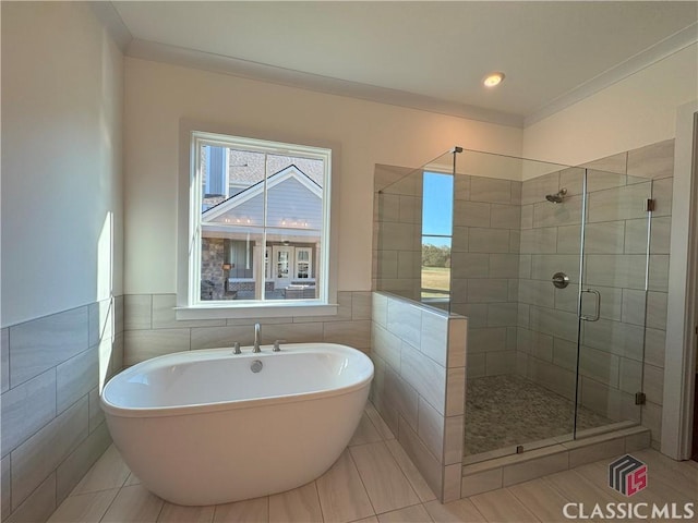 full bath featuring a stall shower, tile walls, a freestanding bath, and wainscoting