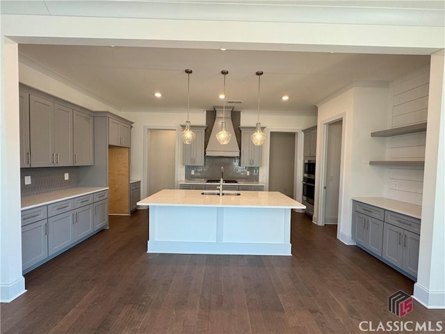 kitchen with dark wood-type flooring, a sink, gray cabinets, open shelves, and custom range hood