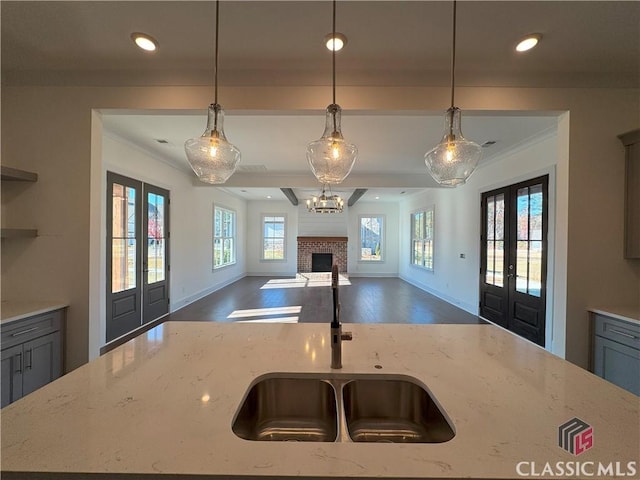 kitchen featuring french doors, a fireplace, decorative light fixtures, and light stone countertops