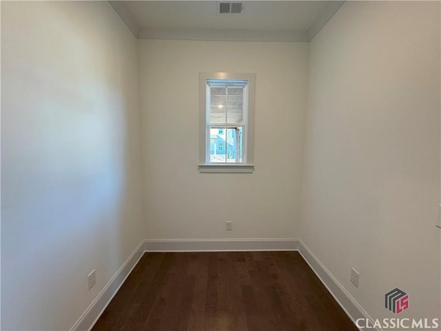 unfurnished room featuring visible vents, dark wood finished floors, and baseboards