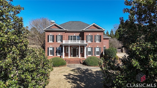 colonial house featuring a balcony and brick siding