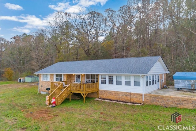 ranch-style house with roof with shingles, a front yard, stairway, and an outdoor structure