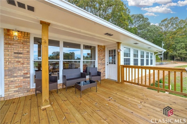 wooden deck featuring outdoor lounge area and visible vents