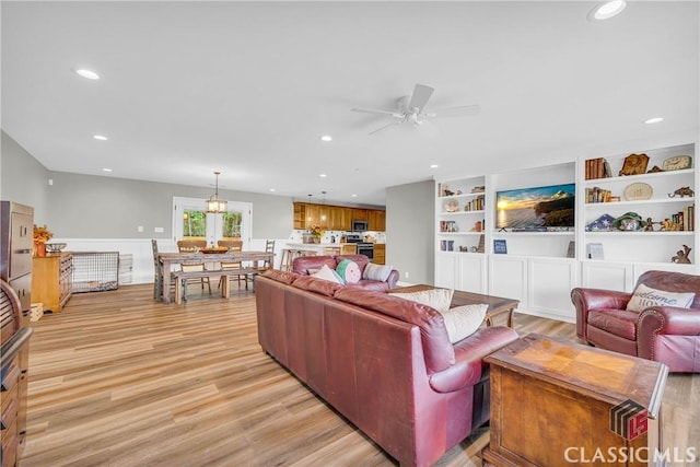 living area with a ceiling fan, recessed lighting, light wood-style flooring, and built in shelves