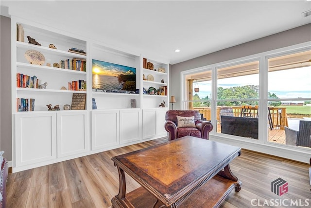 living room with built in features, light wood-type flooring, visible vents, and recessed lighting