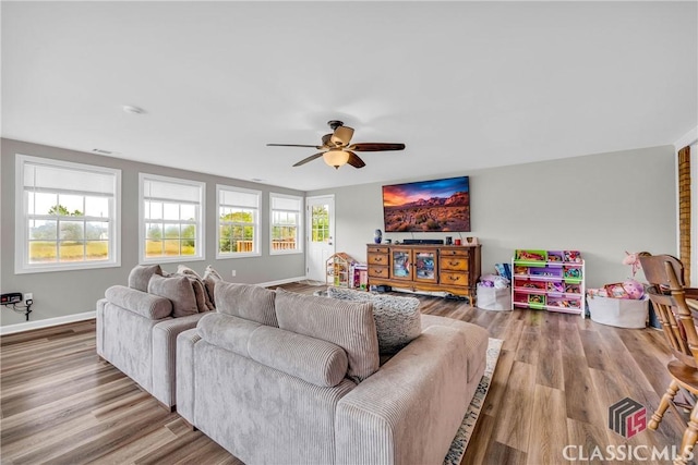 living room featuring a ceiling fan, baseboards, and wood finished floors