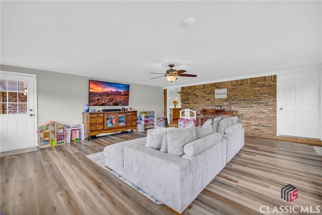 living area featuring brick wall, a ceiling fan, and wood finished floors