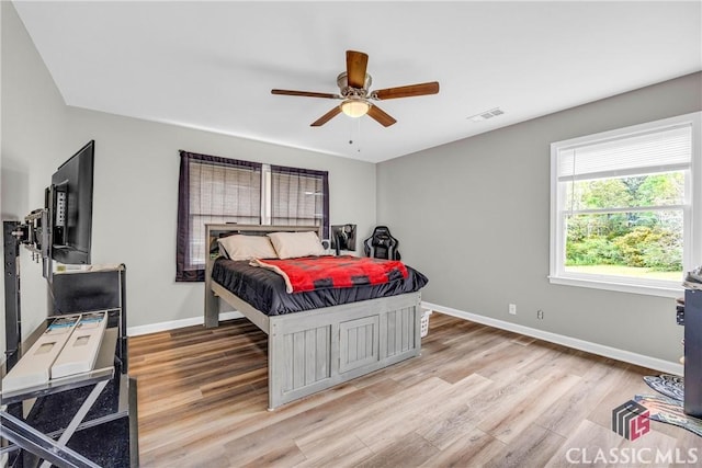 bedroom with ceiling fan, light wood-type flooring, visible vents, and baseboards