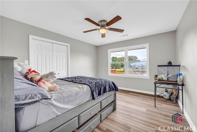 bedroom featuring a closet, visible vents, light wood-style floors, ceiling fan, and baseboards