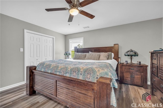 bedroom featuring a closet, visible vents, baseboards, and wood finished floors