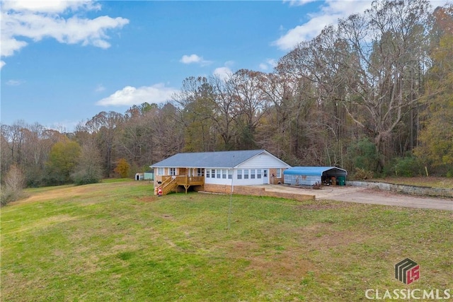 single story home featuring a forest view, driveway, and a front lawn