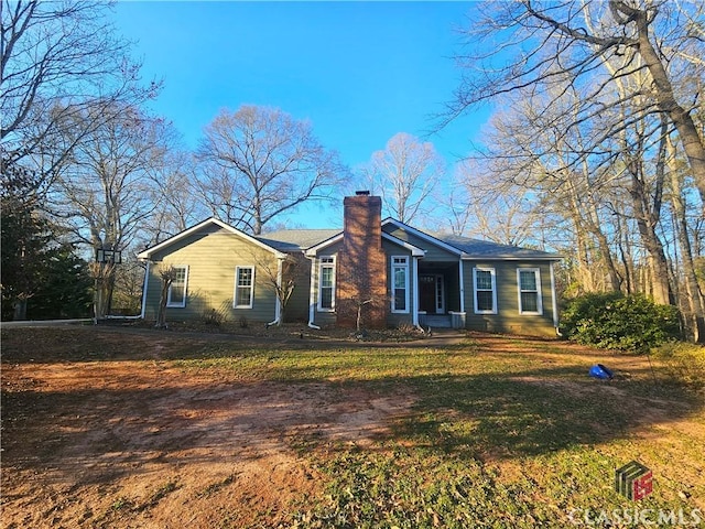 view of front facade with a chimney and a front lawn