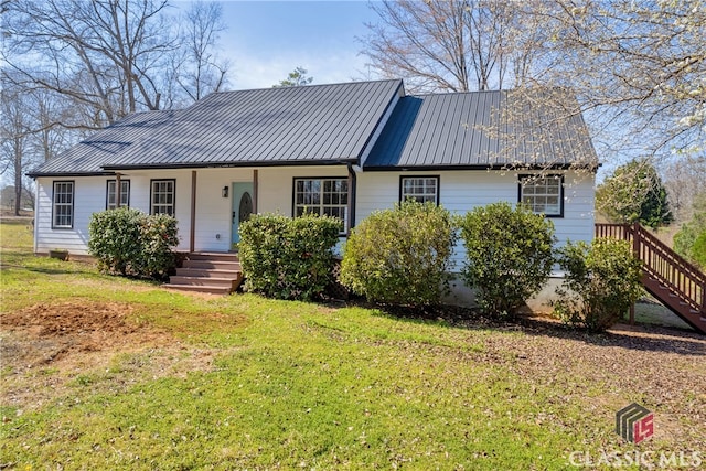 ranch-style home featuring covered porch, metal roof, and a front yard