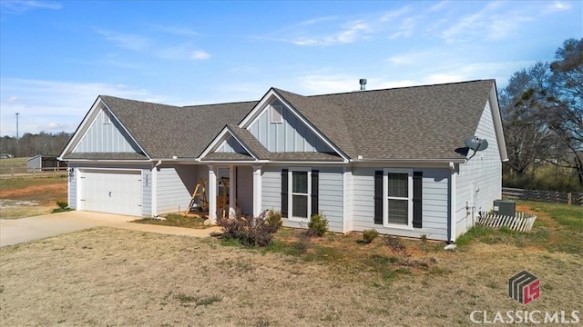 view of front facade with a shingled roof, concrete driveway, board and batten siding, fence, and a garage