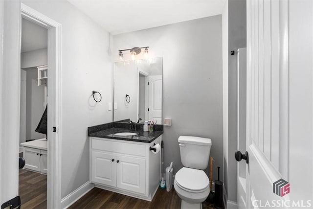 bathroom featuring toilet, baseboards, wood finished floors, and vanity