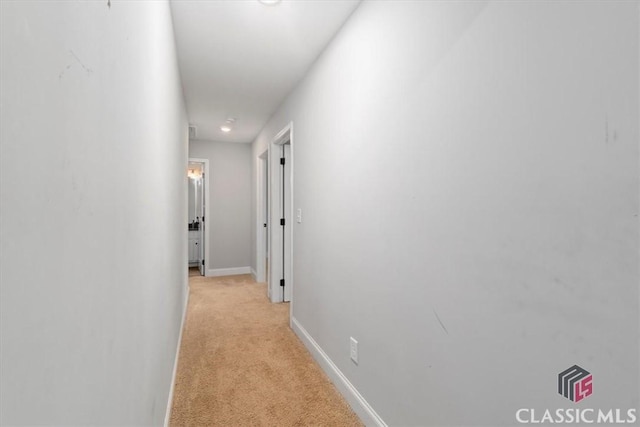 hallway featuring baseboards and light colored carpet