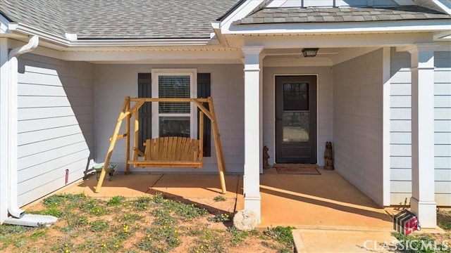 view of exterior entry featuring a shingled roof and a porch