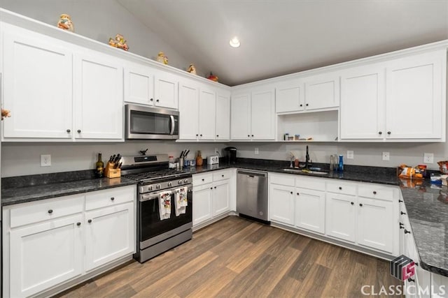 kitchen with dark wood finished floors, white cabinets, lofted ceiling, stainless steel appliances, and a sink