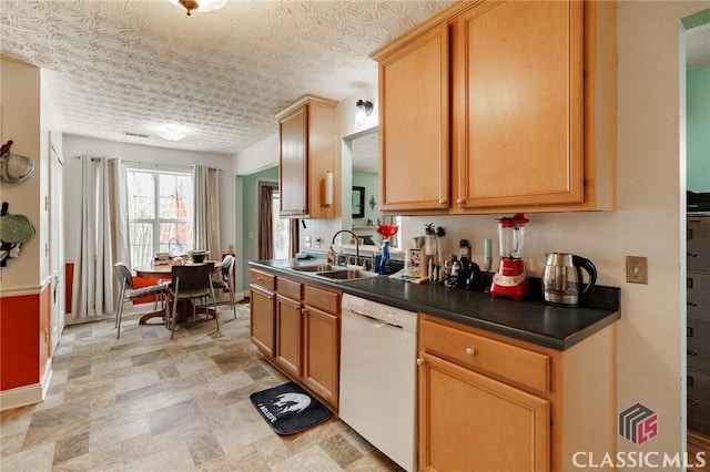 kitchen with baseboards, dark countertops, white dishwasher, a textured ceiling, and a sink