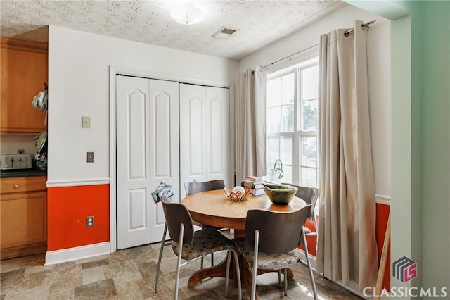 dining room with visible vents, baseboards, and a textured ceiling