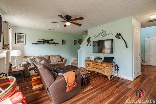 living area featuring visible vents, a ceiling fan, wood finished floors, stairs, and a textured ceiling