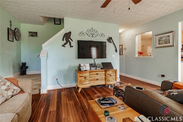 living area featuring baseboards, a textured ceiling, a ceiling fan, and wood finished floors