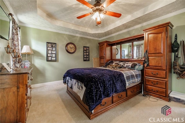 bedroom featuring baseboards, a raised ceiling, light colored carpet, ornamental molding, and a textured ceiling