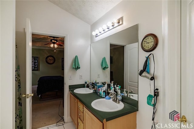 ensuite bathroom with lofted ceiling, double vanity, a textured ceiling, and a sink