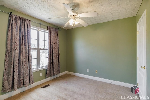 carpeted spare room featuring baseboards, visible vents, ceiling fan, and a textured ceiling