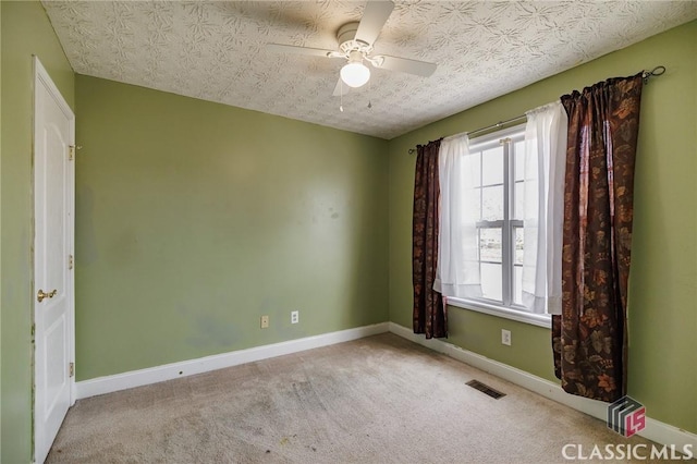 spare room featuring visible vents, a ceiling fan, carpet flooring, a textured ceiling, and baseboards