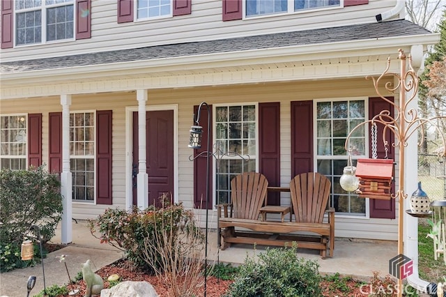 entrance to property with covered porch and roof with shingles