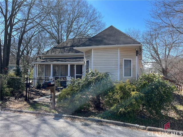 view of side of home featuring a shingled roof and fence