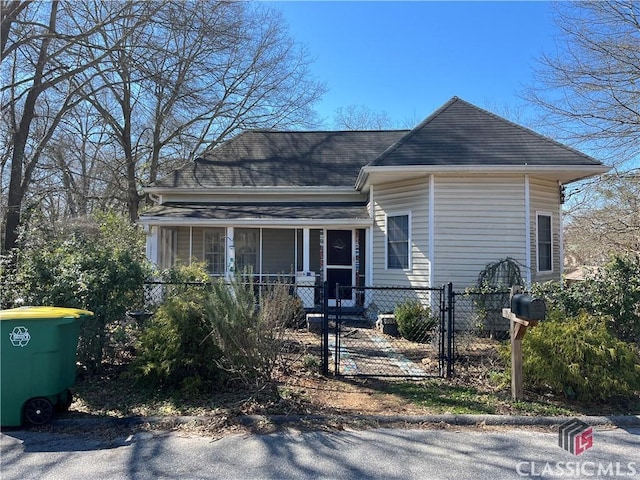 view of front of property with a shingled roof, a fenced front yard, and a gate