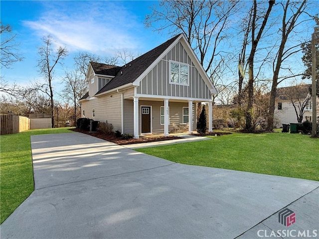 view of front facade featuring a porch, concrete driveway, board and batten siding, fence, and a front lawn