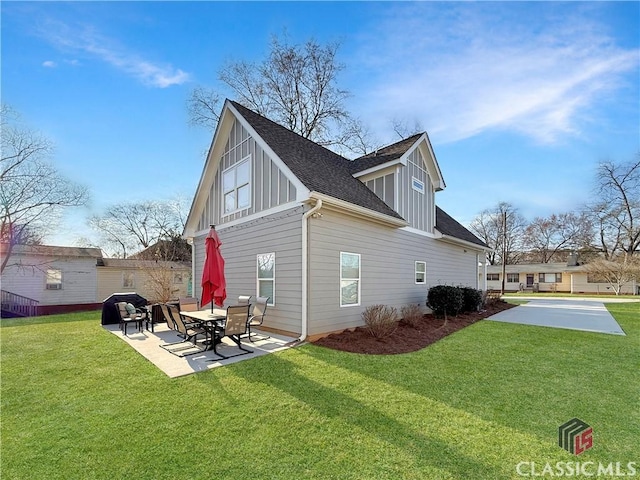 view of side of property featuring a yard, roof with shingles, board and batten siding, and a patio