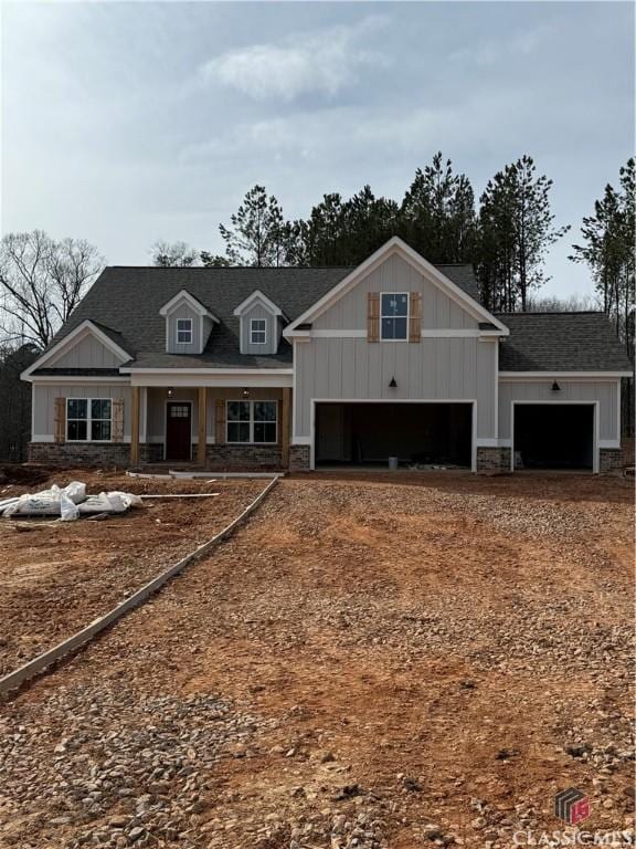 craftsman-style house featuring a garage, driveway, stone siding, roof with shingles, and board and batten siding